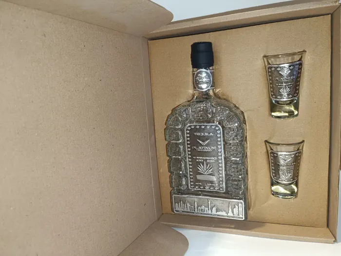 Botella con placa y dos caballitos personalizados dentro de una caja de cartón kraft